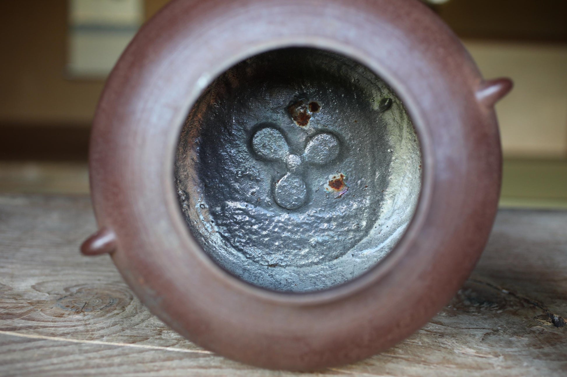 the inside of a brown ceramic container, possibly a teapot or vase, with a metal pattern visible inside.