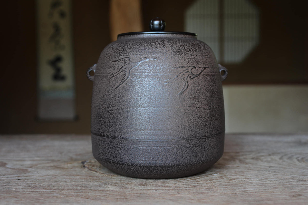 A ceramic teapot with a lid and handle, sitting on a wooden surface.