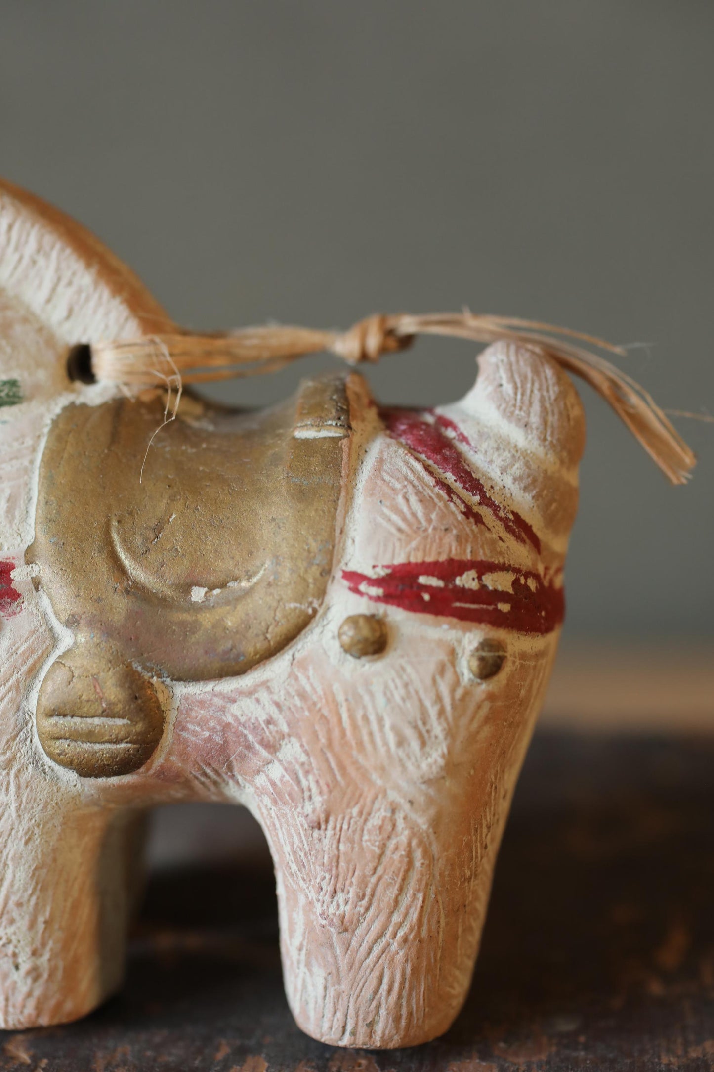 A close-up image of a small, white ceramic figurine of a horse with a red stripe on its face.