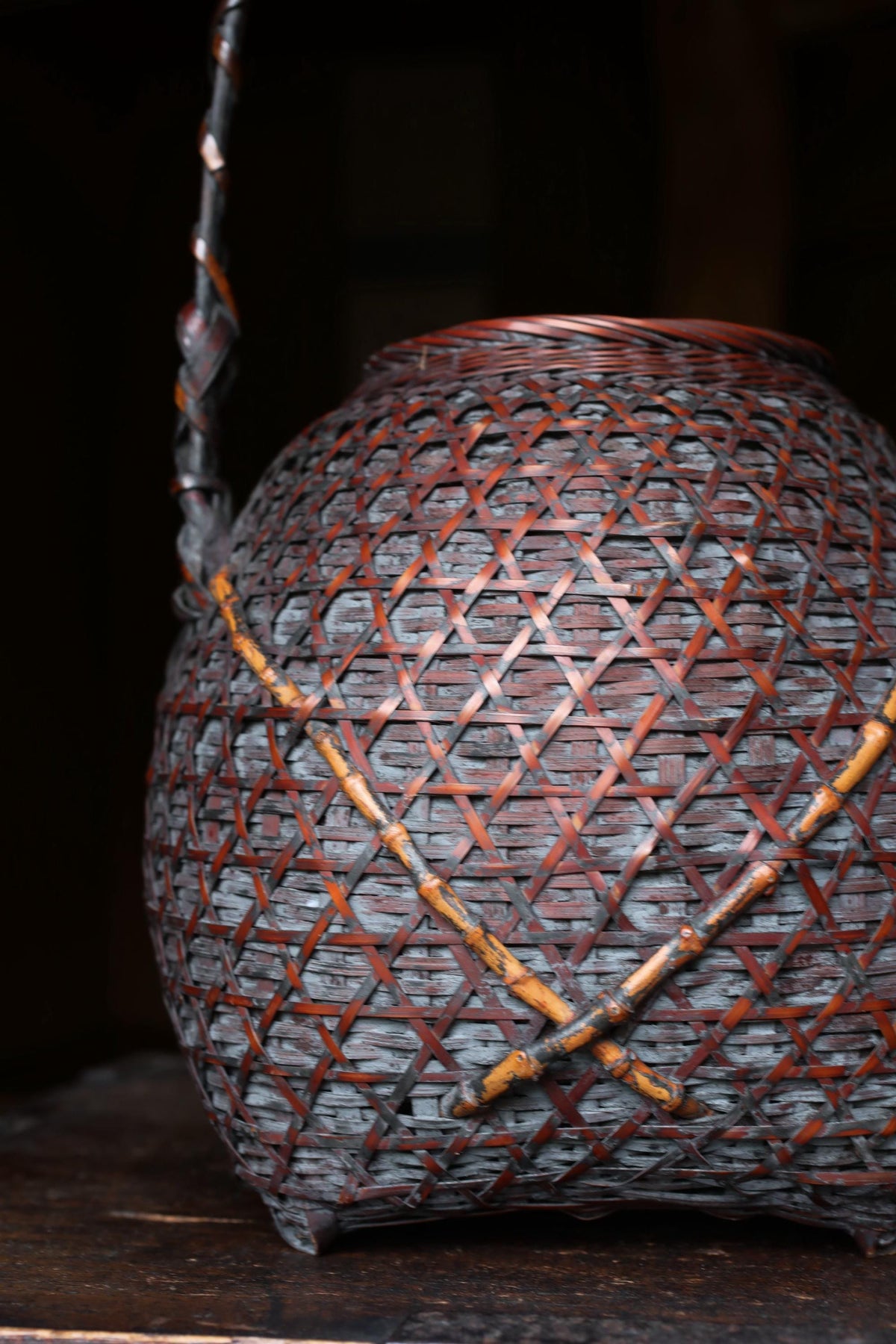 A close-up view of a woven basket with a distinctive pattern of orange and brown interwoven strands.