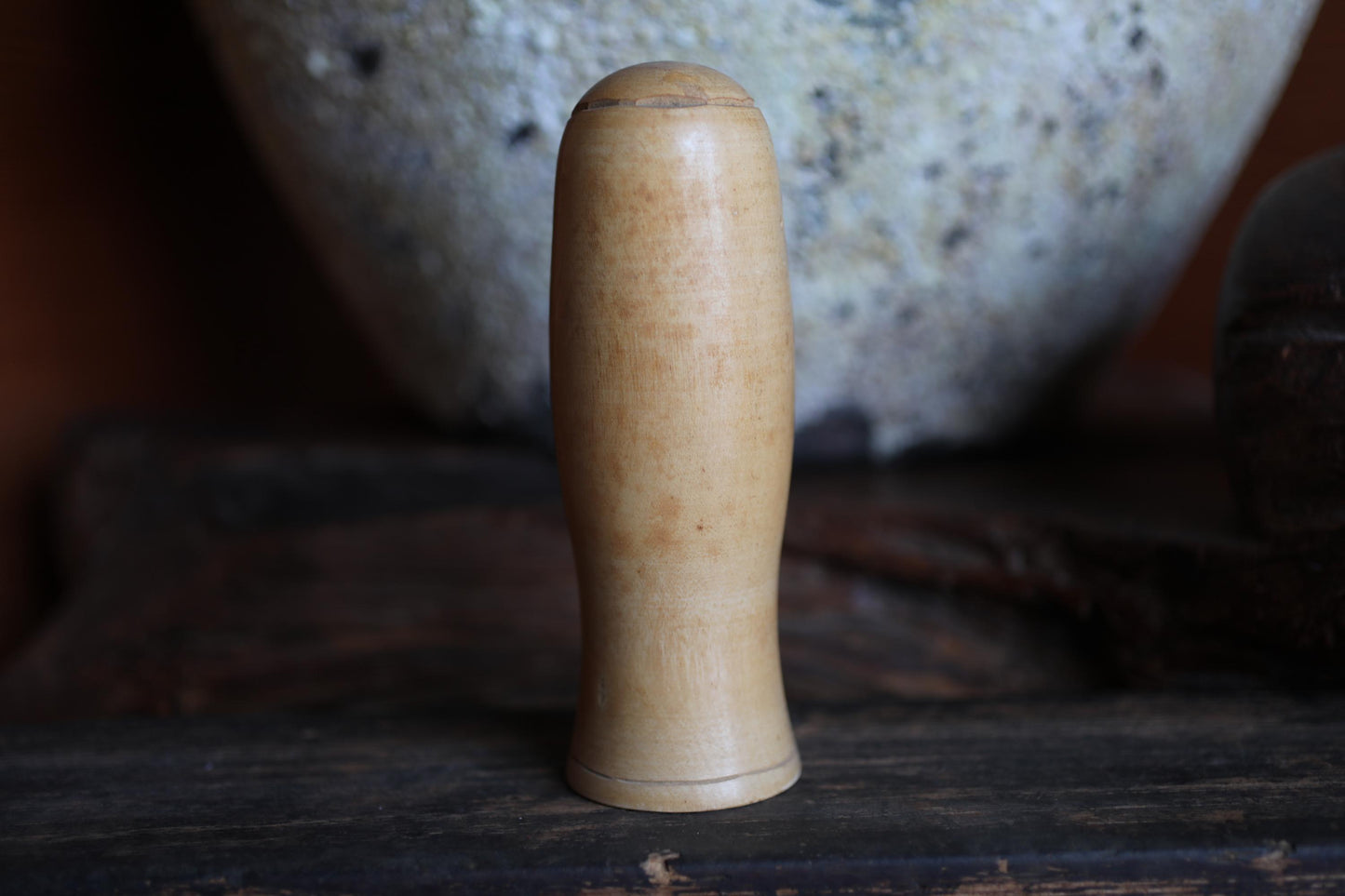 A wooden object with a curved shape, possibly a handle or a tool, is placed on a wooden surface in the foreground.