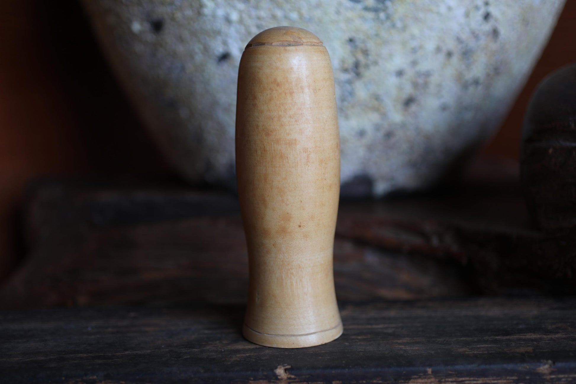 A wooden object with a curved shape, possibly a handle or a tool, is placed on a wooden surface in the foreground.