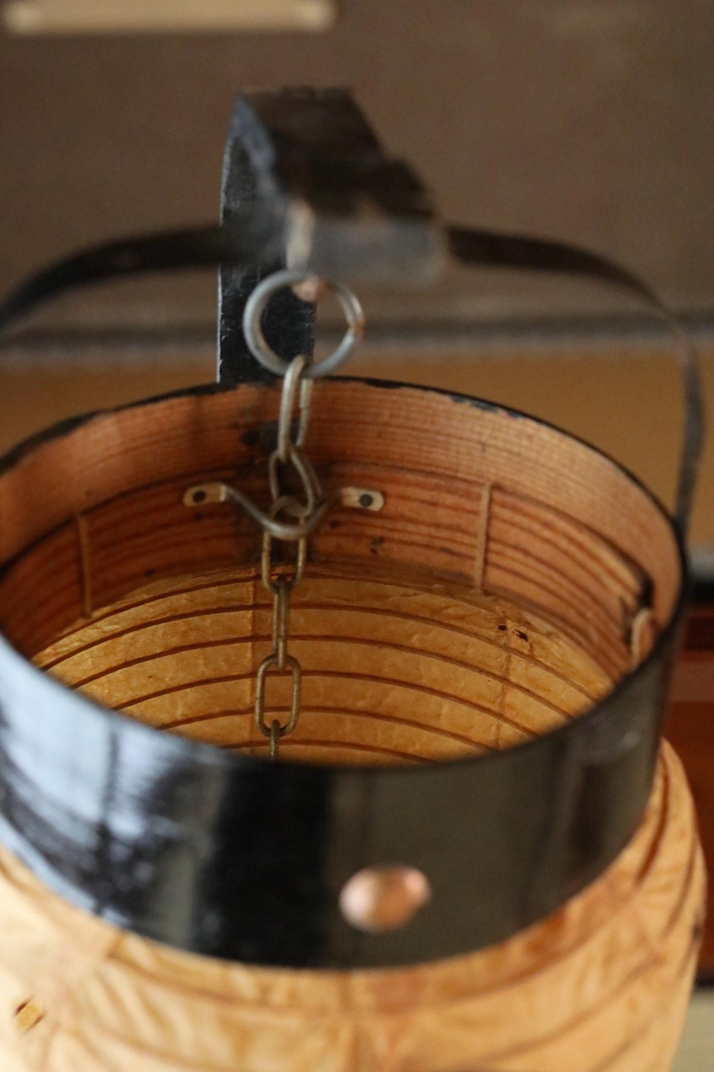 A black metal object with a chain hanging from it, placed on a wooden surface.