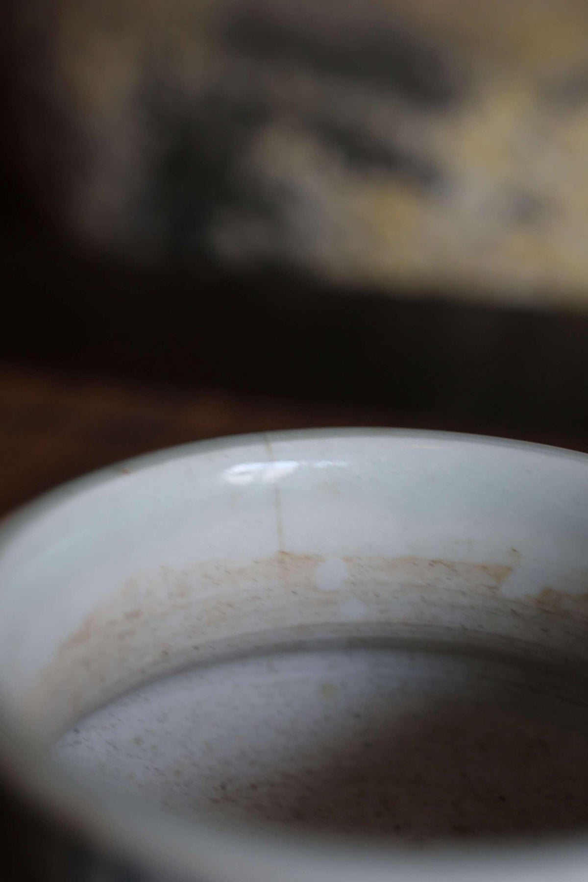 A close-up view of a white ceramic mug or bowl with visible stains or marks on its surface.