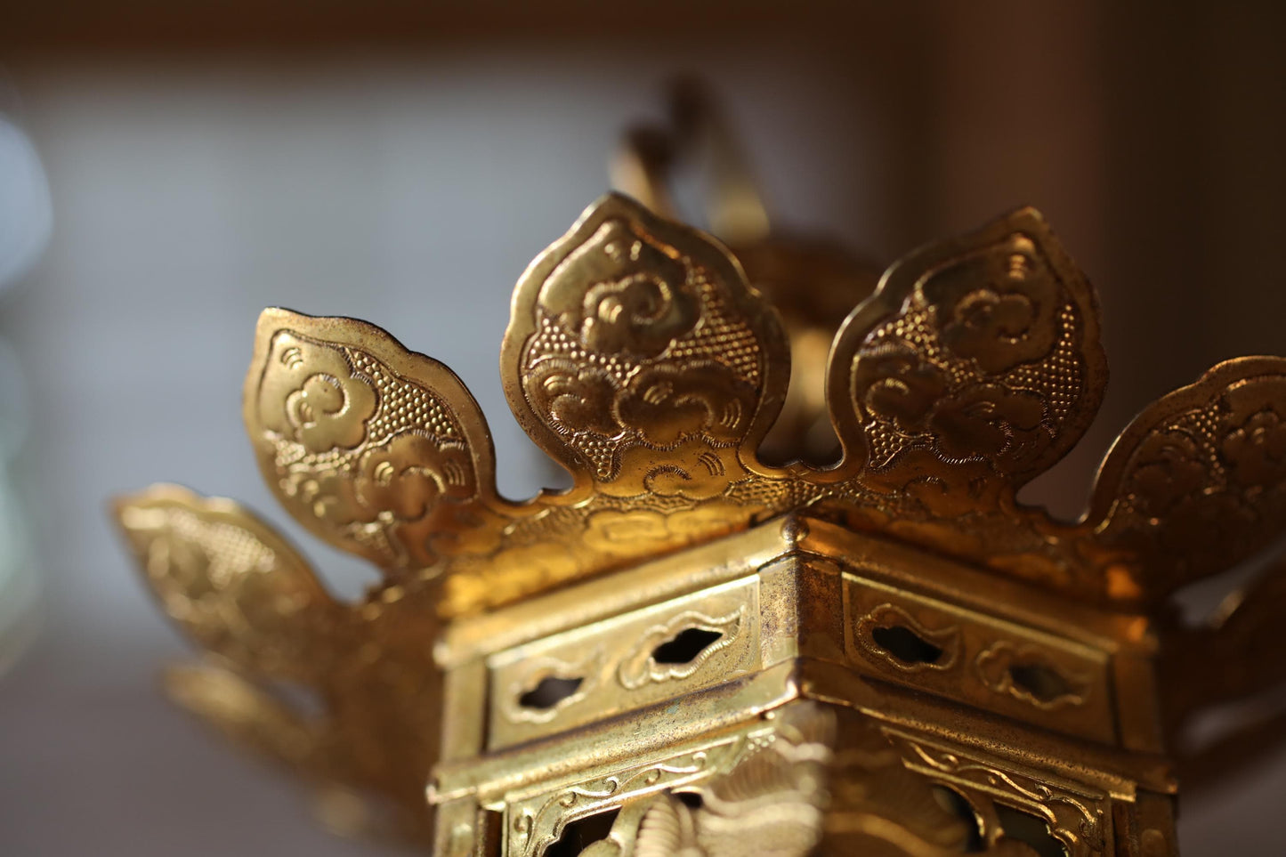 A close-up view of a golden, ornate object with intricate designs and patterns, including floral and geometric motifs.