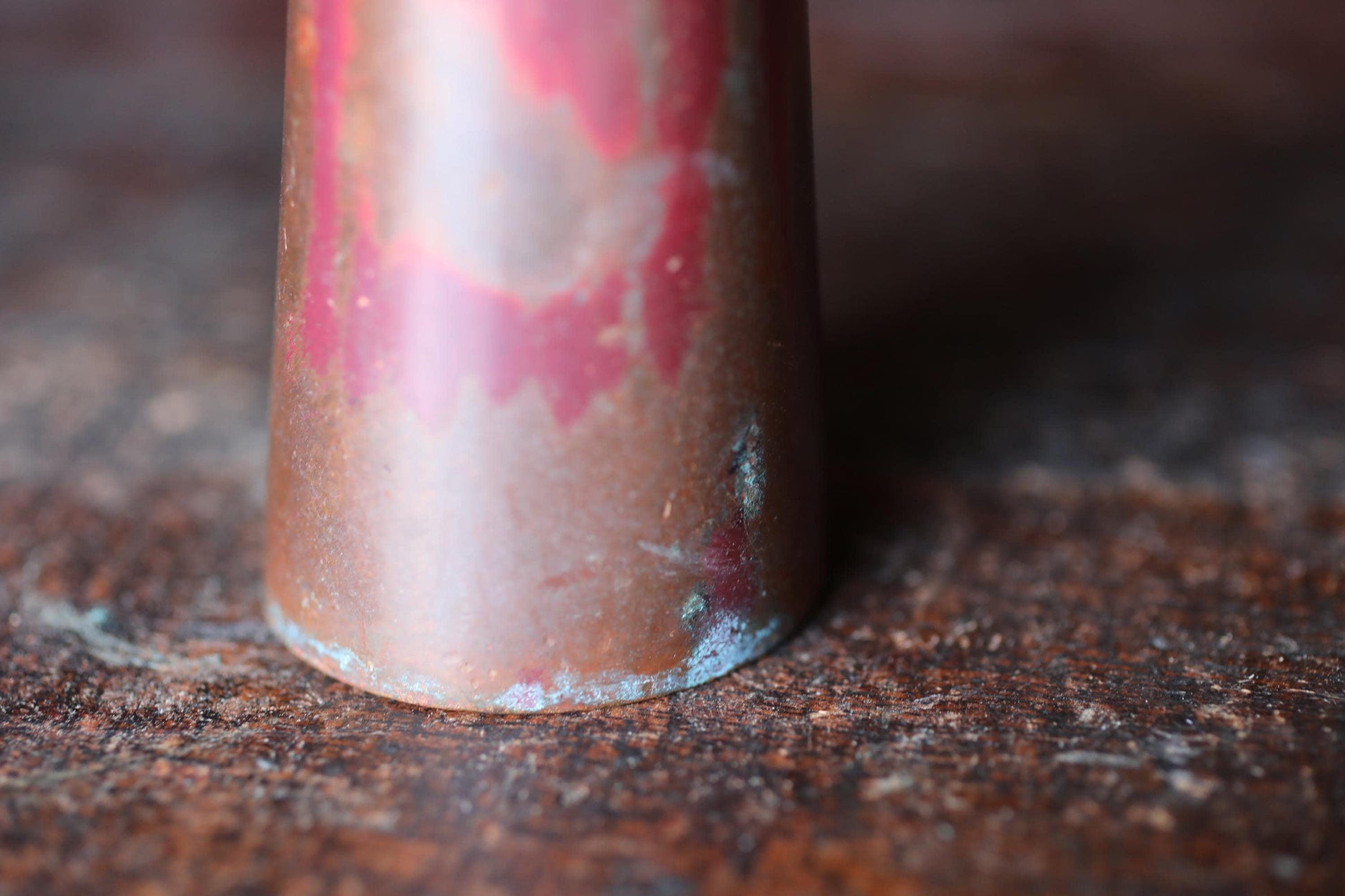A close-up view of a rusted metal object, possibly a piece of furniture or a decorative item, with a reddish-brown color and visible rust or corrosion.
