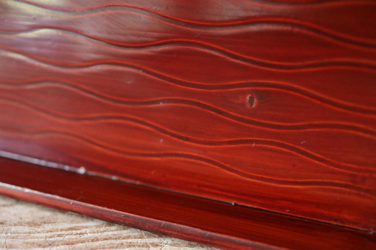a close-up view of a wooden surface with a distinctive wavy pattern, likely made of a dark-colored wood.