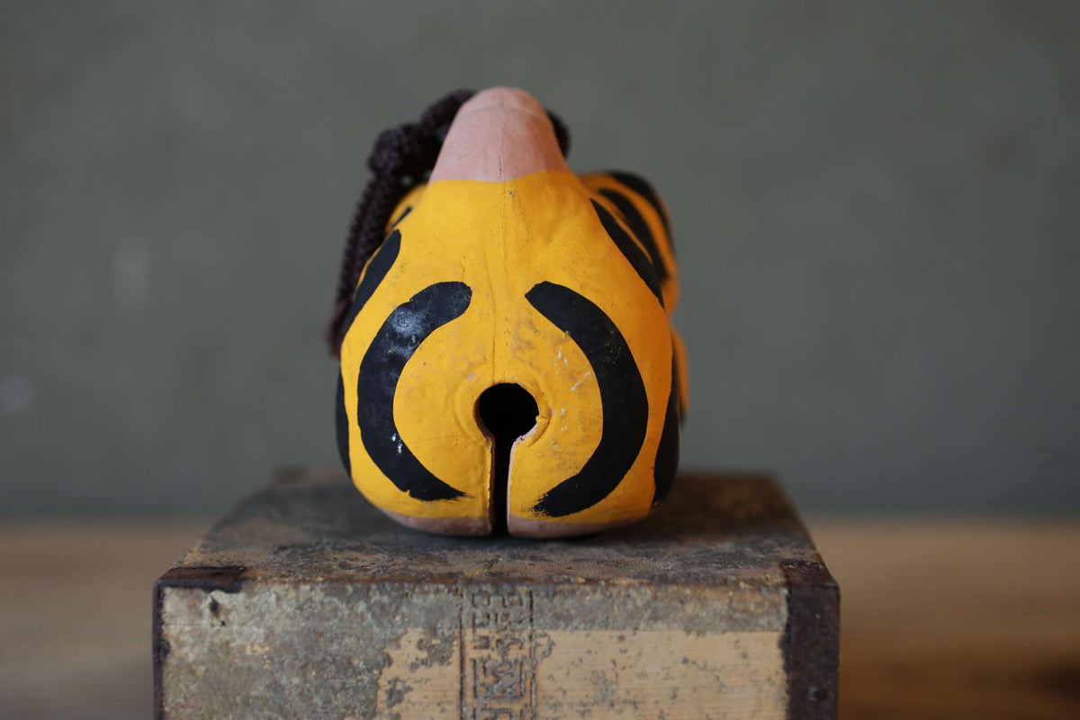 A yellow and black striped object, possibly a toy or figurine, is sitting on a wooden surface.