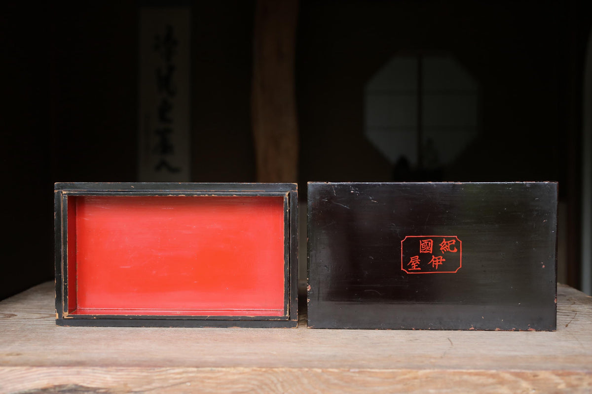 two wooden boxes, one with a red interior and the other with a black interior, placed on a wooden surface.