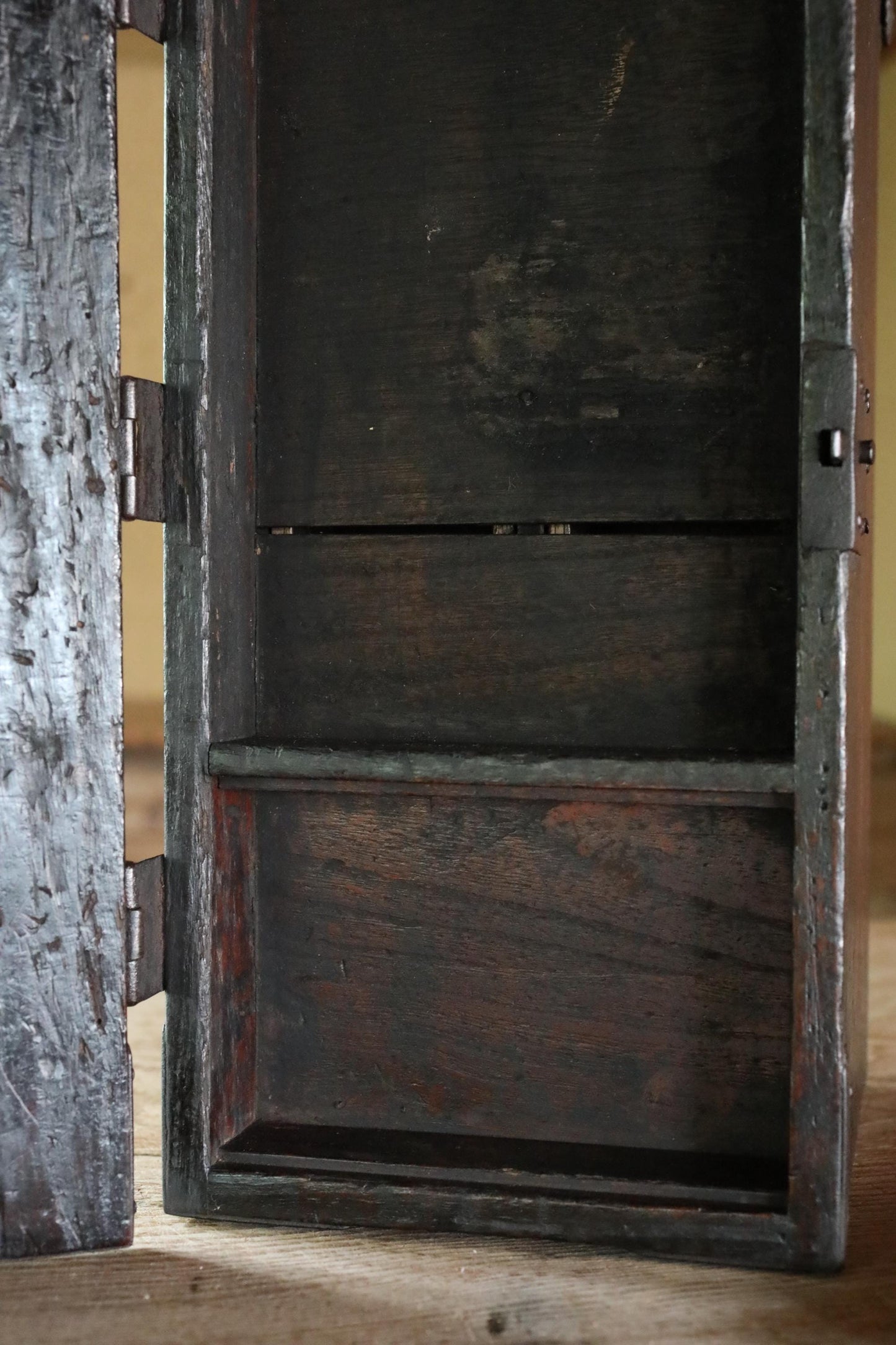 an old, wooden cabinet with a dark finish, sitting on a wooden surface.