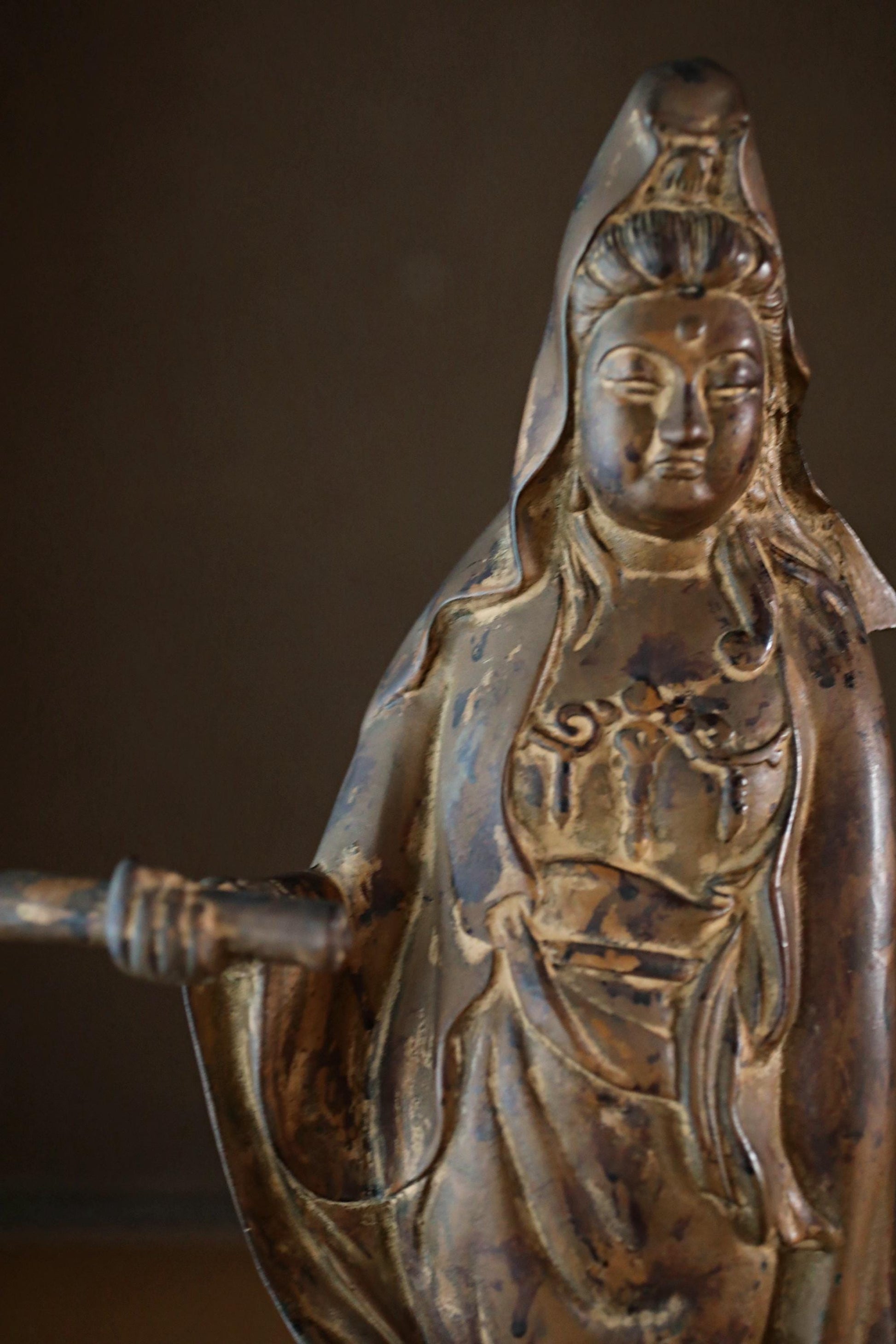 A bronze statue of a deity, possibly a Buddhist figure, with intricate details and a serene expression.