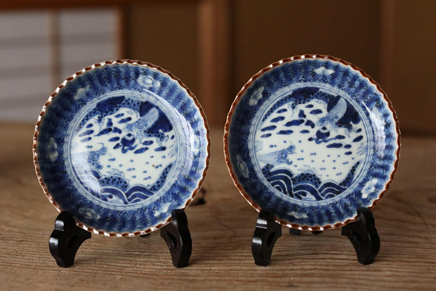 two blue and white plates with intricate designs, displayed on a wooden surface.