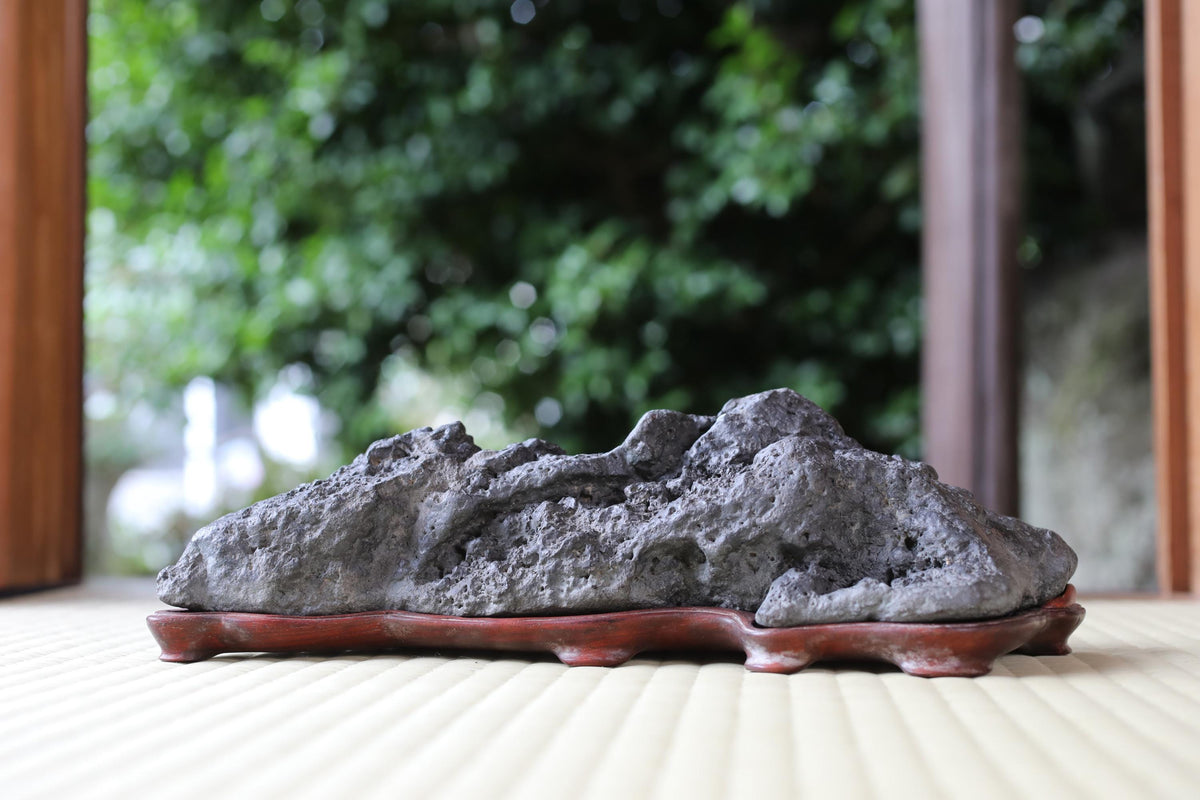 A large, gray rock sits on a wooden base, placed on a white surface.
