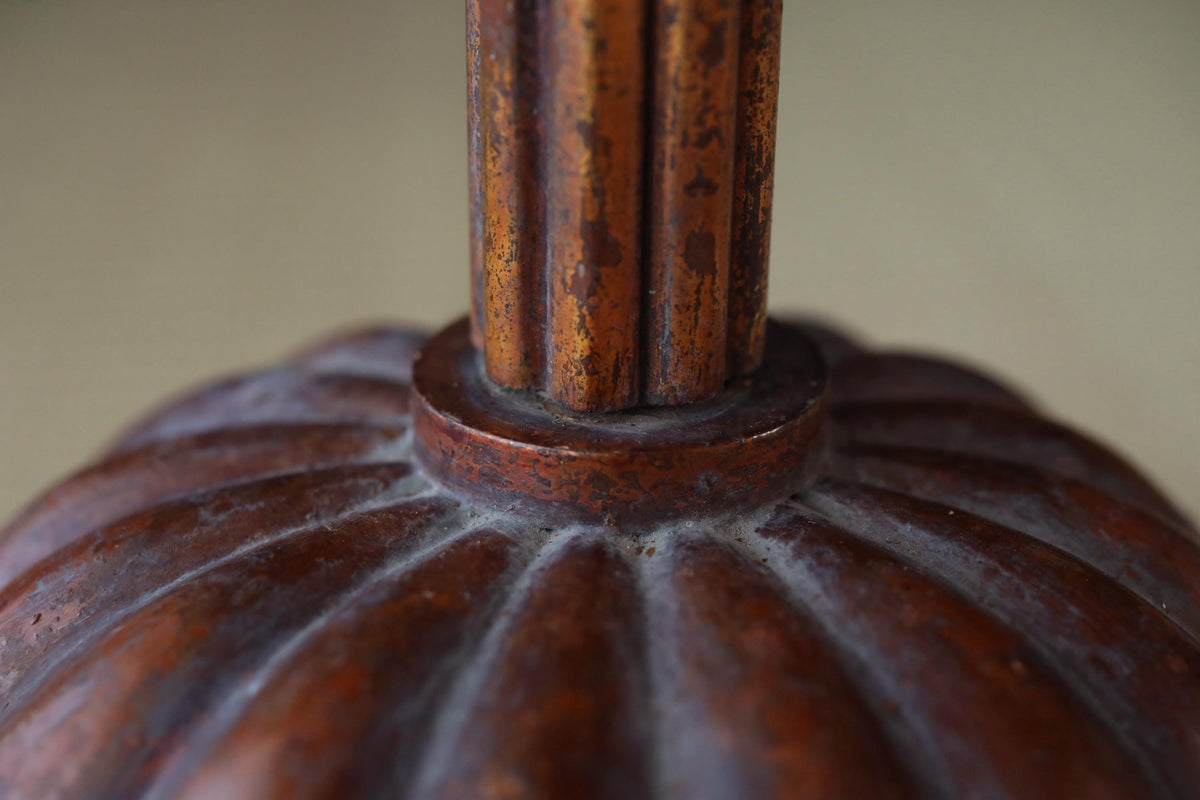 A close-up view of a rusted metal base with a decorative design, likely a lamp or table base.