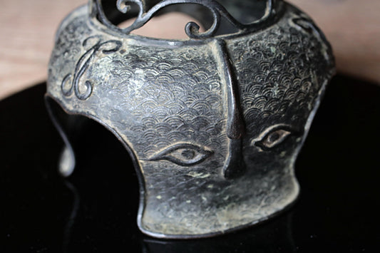 a close-up view of a decorative metal object, possibly a piece of jewelry or a sculpture, with intricate patterns and designs.