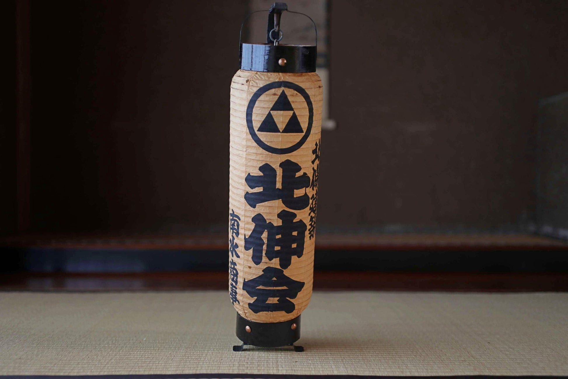 A traditional Japanese paper lantern with a black and white design and Japanese text.
