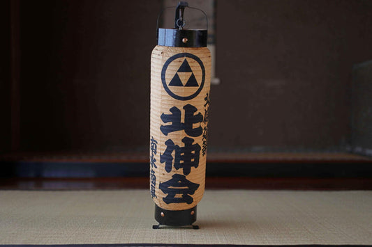 A traditional Japanese paper lantern with a black and white design and Japanese text.