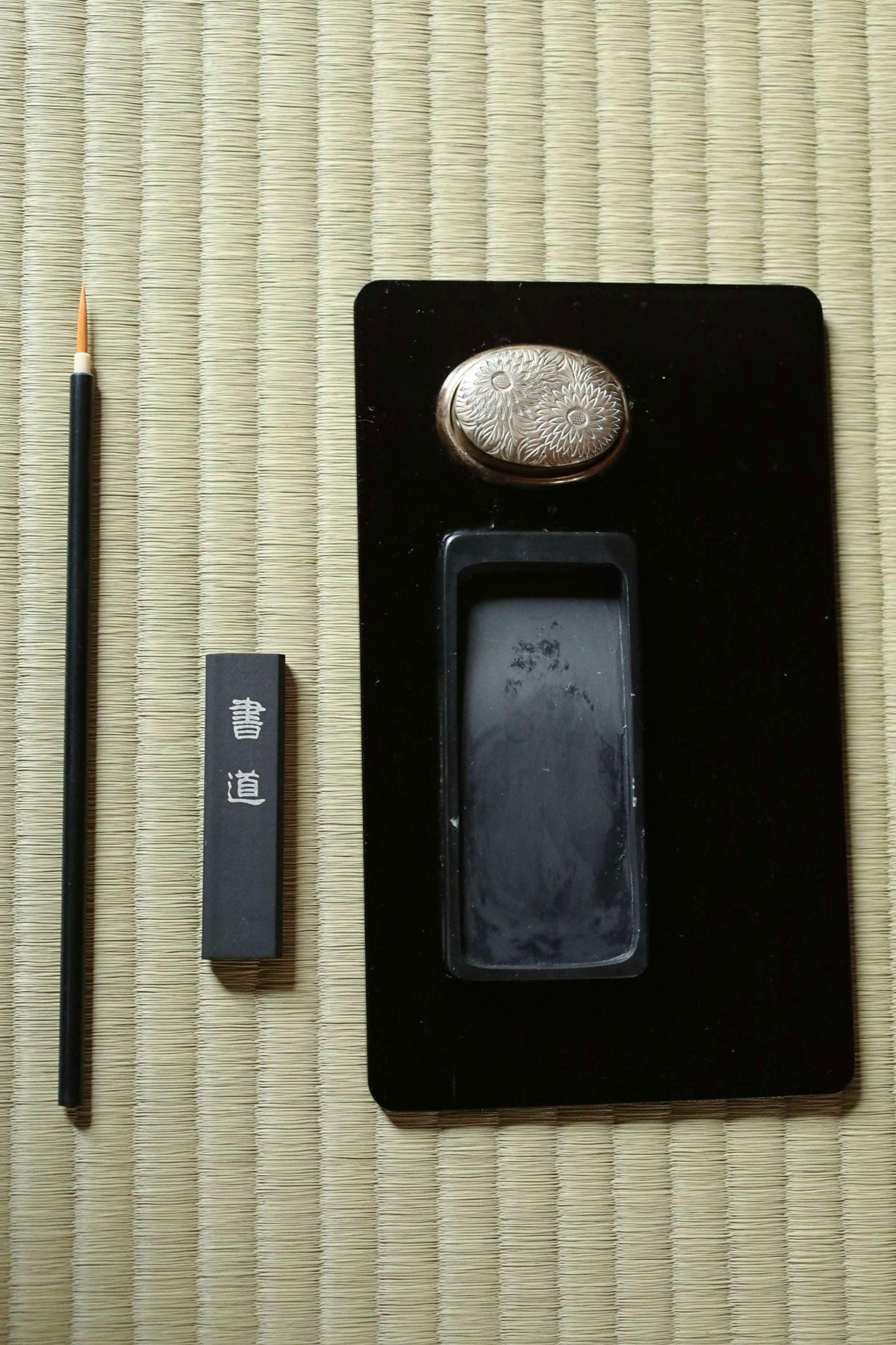a black frame with a small black object on top, a black pencil, and a small black object on the left side.