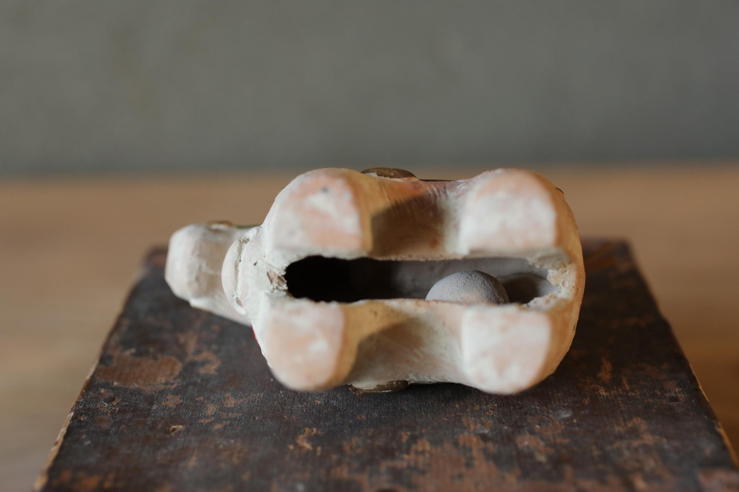 A ceramic elephant figurine with a hole in its trunk, sitting on a wooden surface.