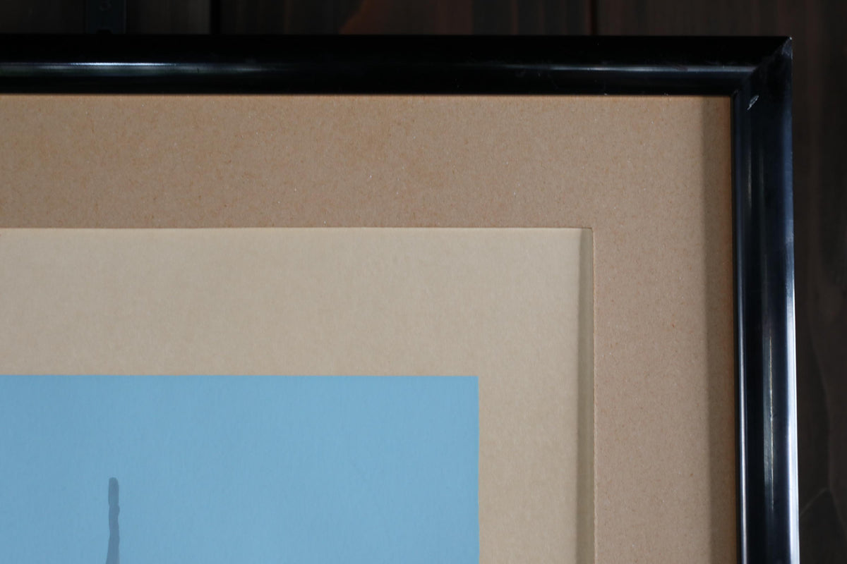 a close-up view of a framed artwork with a black border, showcasing a layered composition of various shades of brown and beige paper.