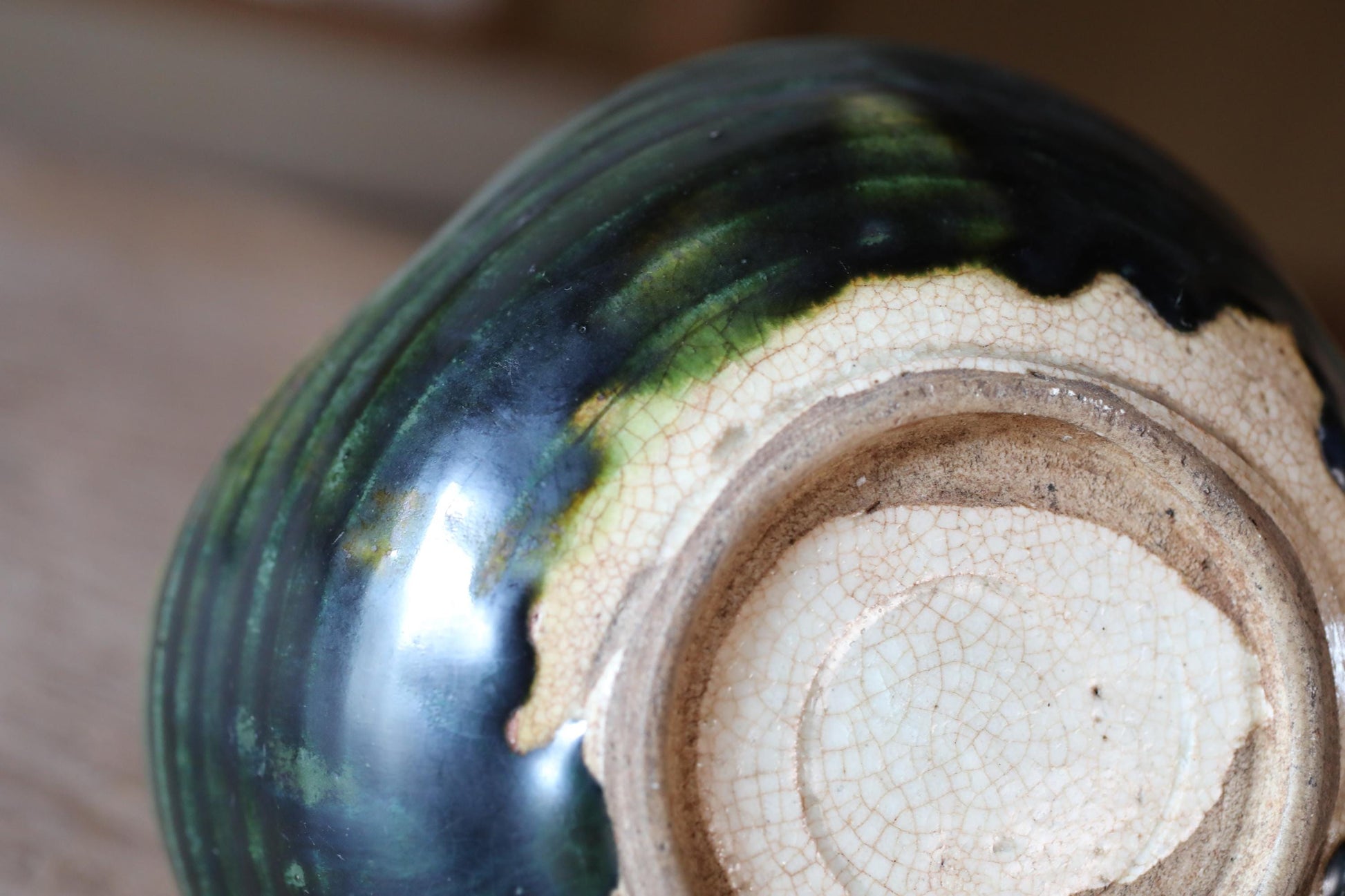 A close-up view of a ceramic vase with a green and white glaze, showing the intricate patterns and textures of the material.