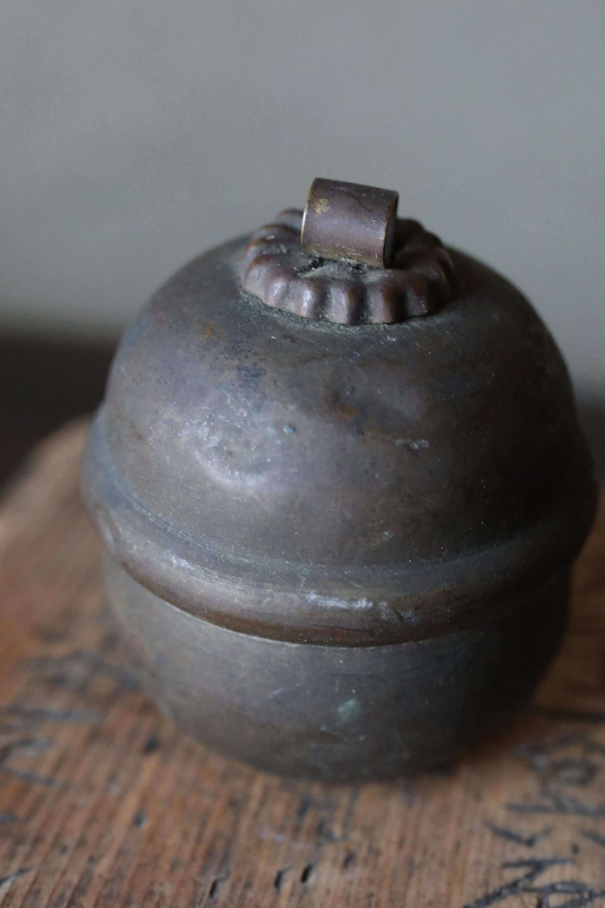 A close-up image of a round, dark-colored metal object with a small, round finial or finial-like element on top.