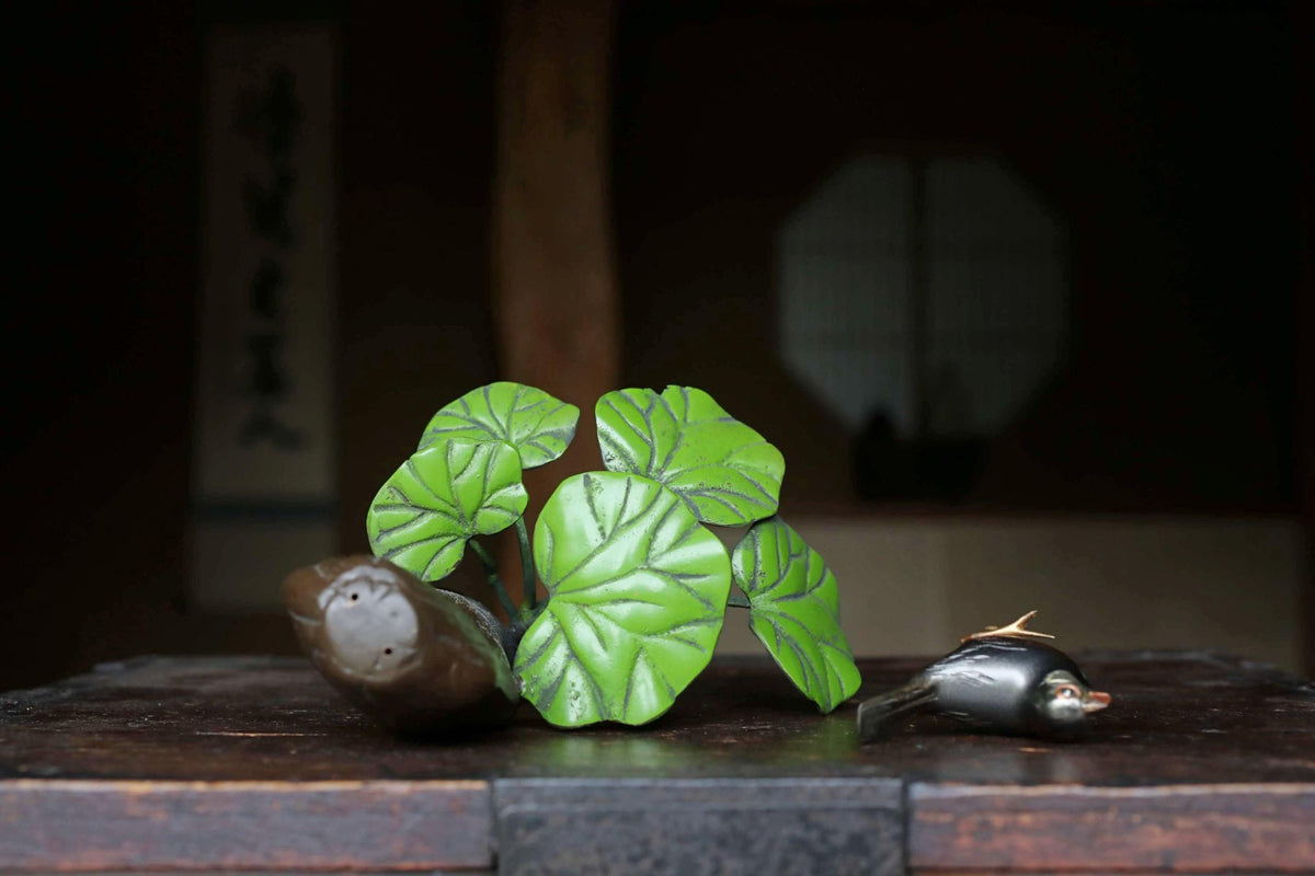 a wooden table with a green plant and a small bird figurine placed on it.