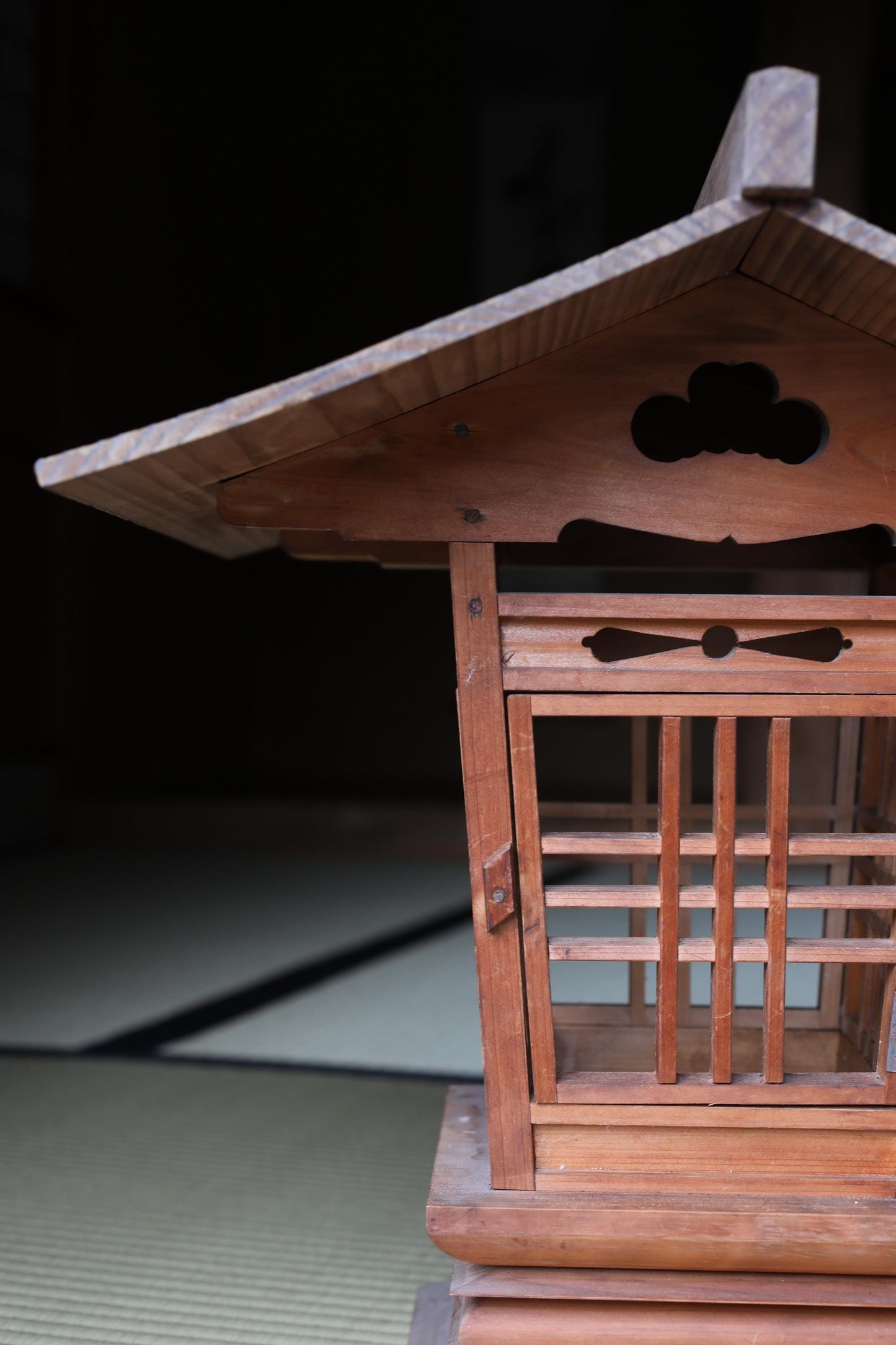 a wooden structure with intricate carvings and a slanted roof, set against a dark background.