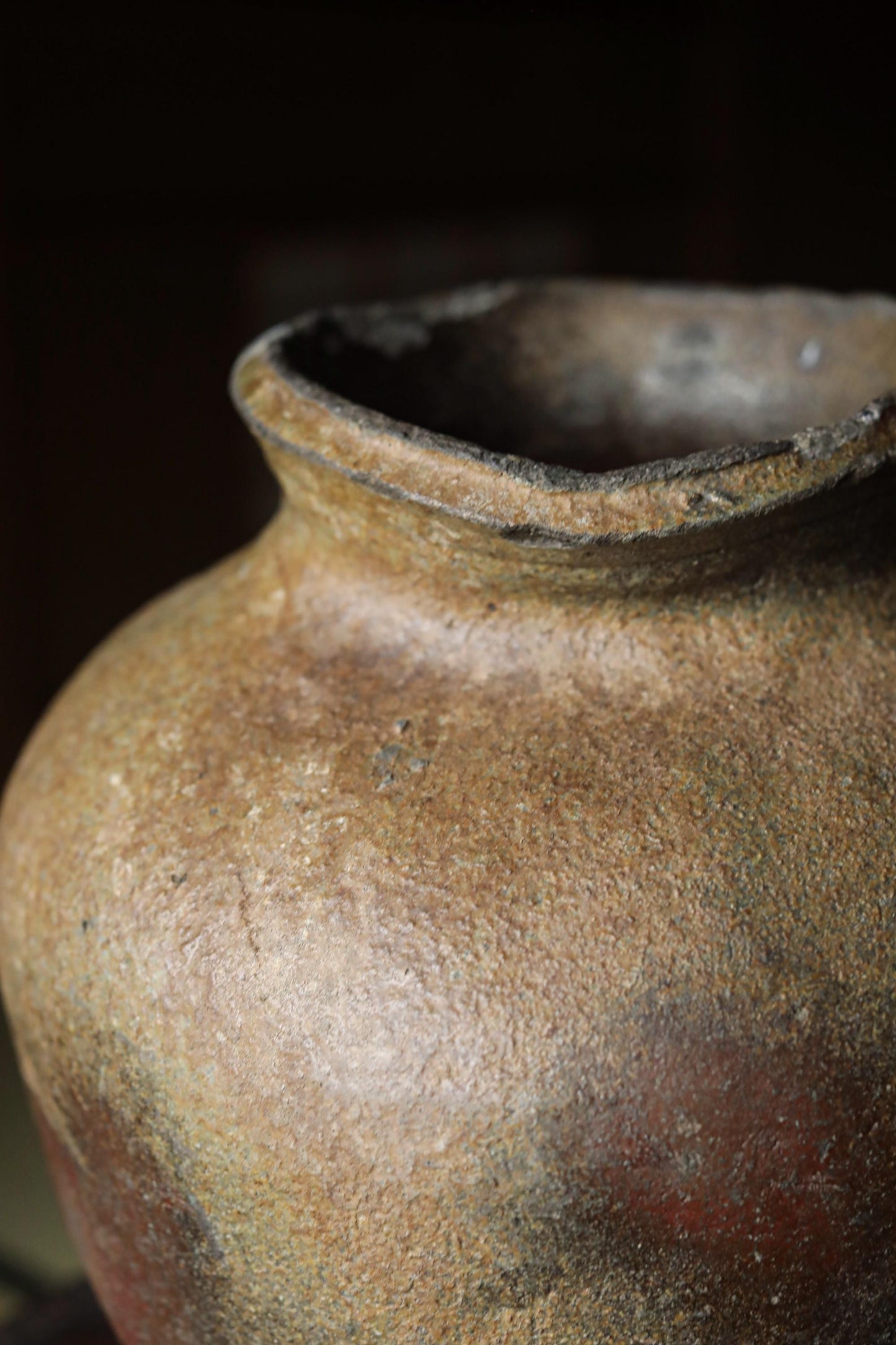 A close-up image of a weathered, brown ceramic vase with a rough, textured surface.