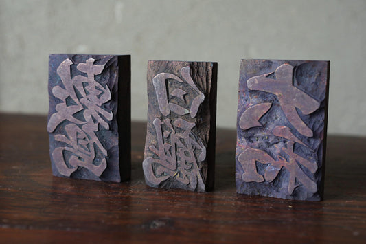 Three rectangular blocks with carved designs on them, placed on a wooden surface.
