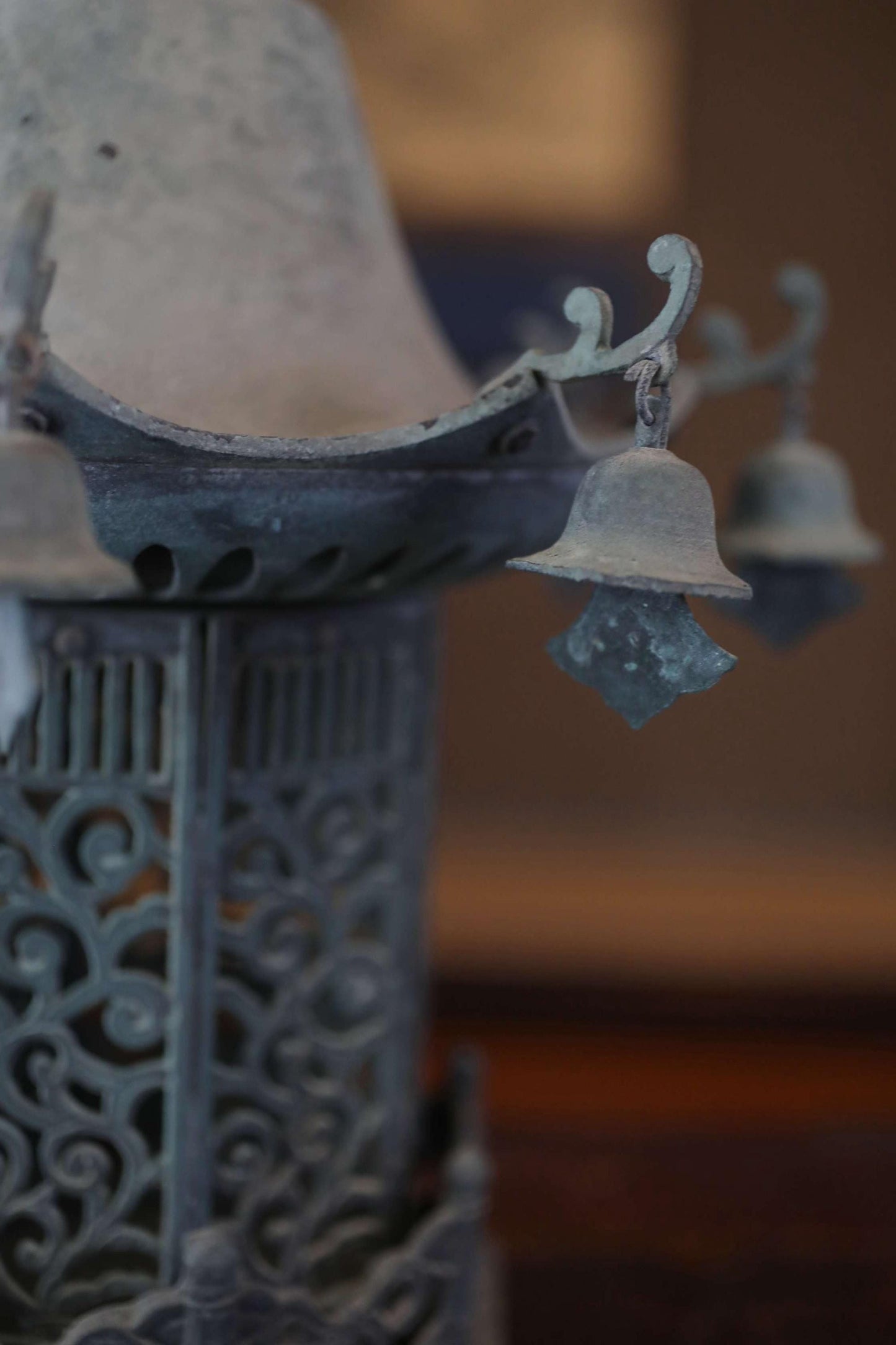 A close-up view of a decorative metal lantern with a curved top and hanging bells.