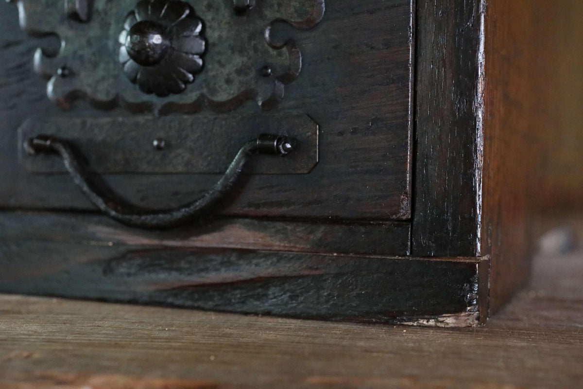 a close-up view of a dark wooden drawer with a metal handle, resting on a wooden surface.