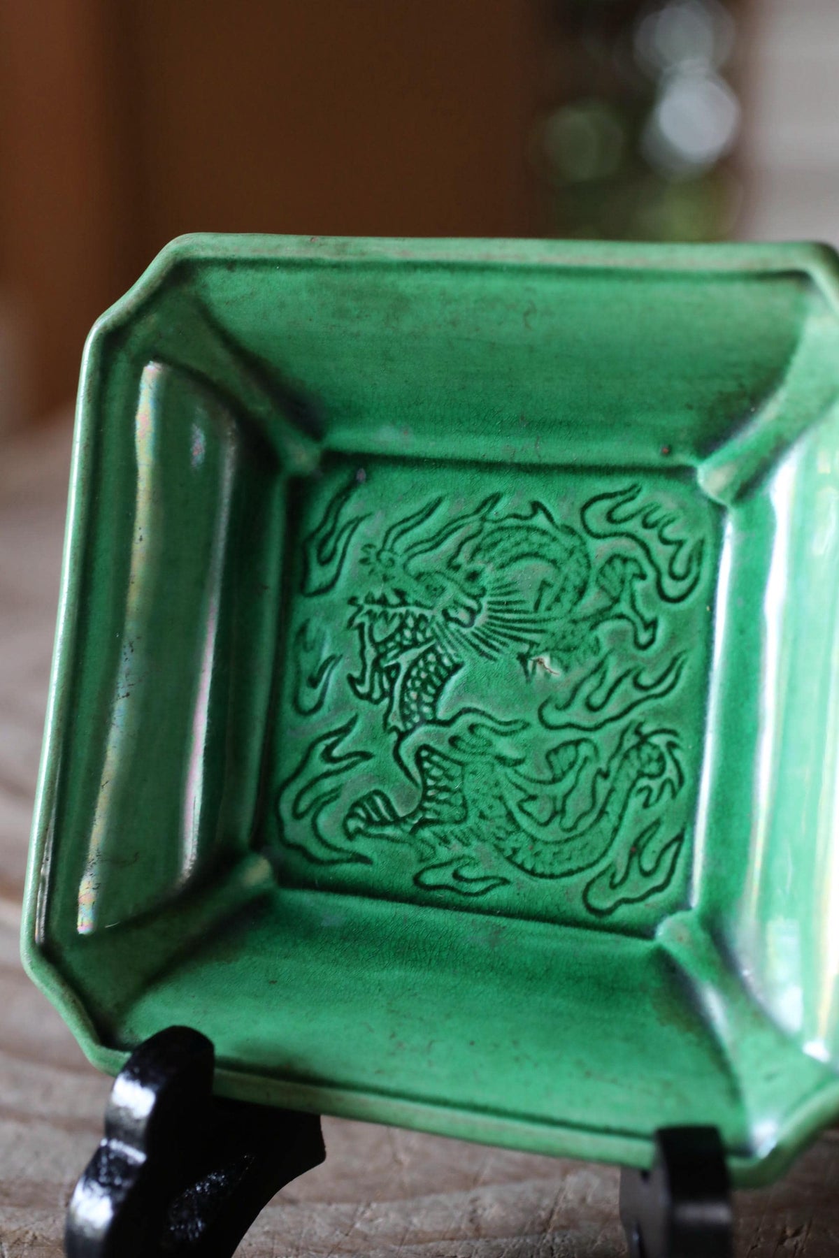 A green ceramic dish with a dragon design on it.