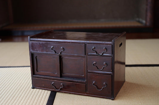 A dark wooden cabinet with multiple drawers and doors sits on a beige mat.