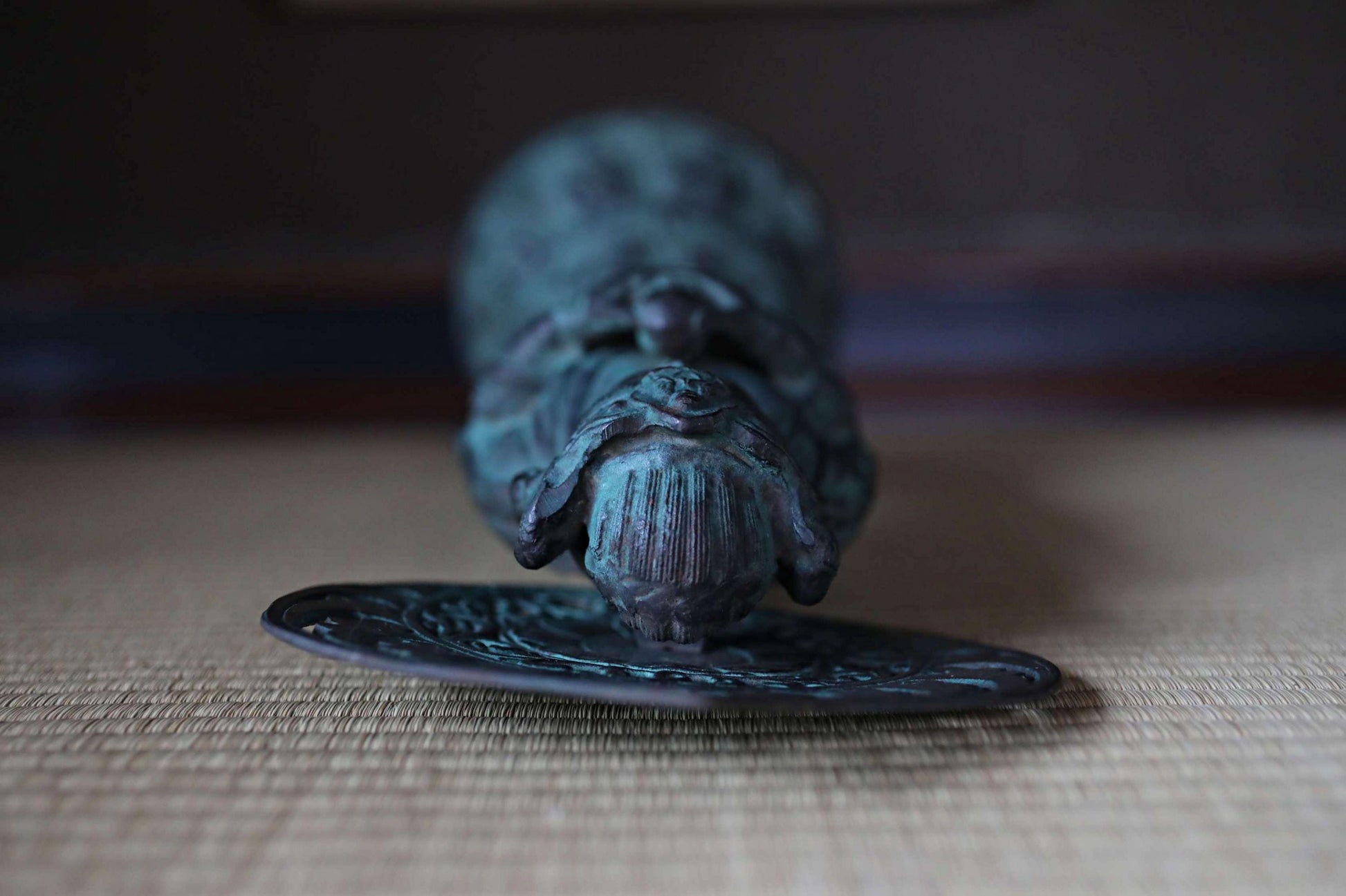 A bronze statue of a person in a meditative pose, sitting on a circular plate with a textured surface.