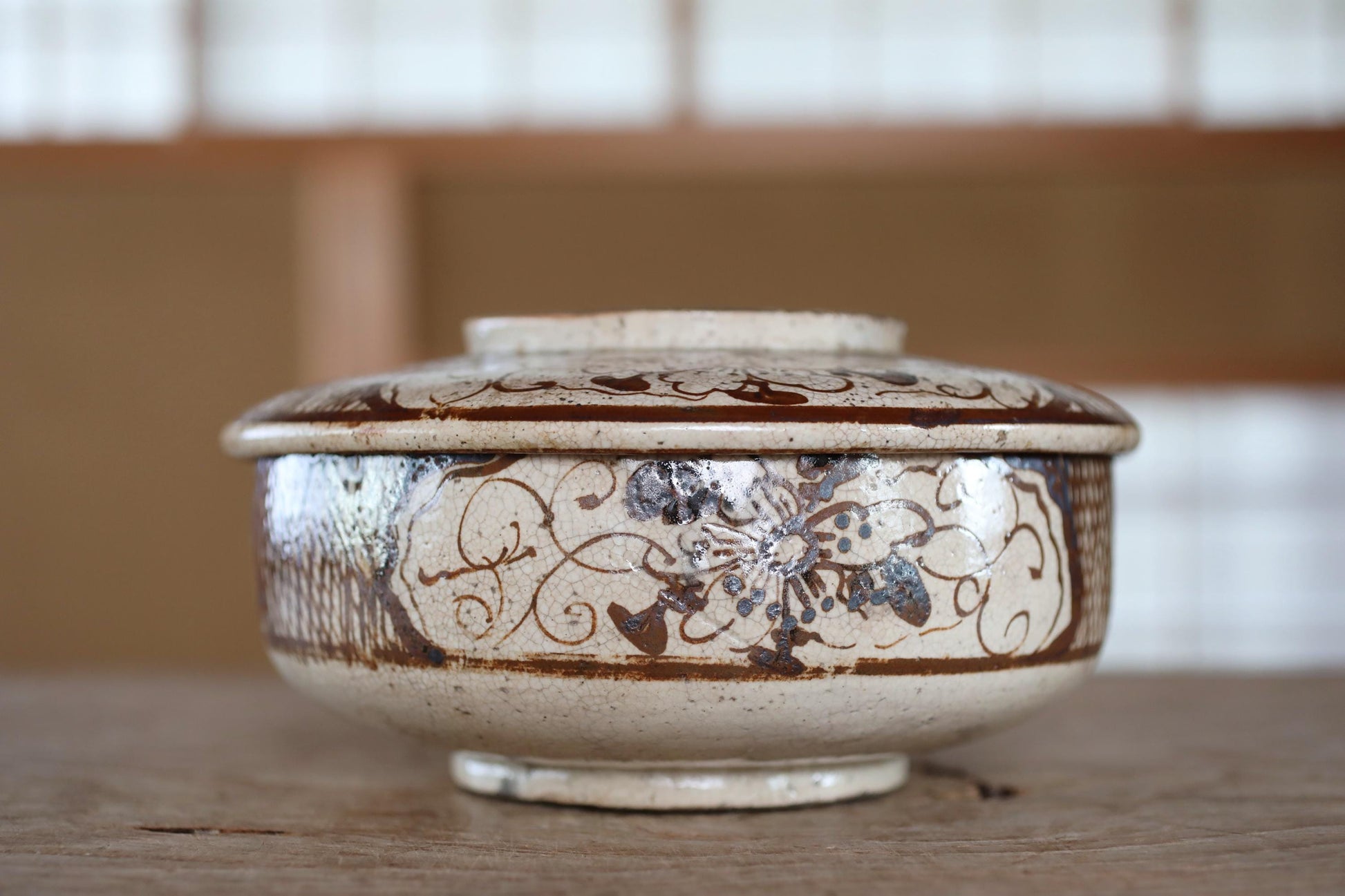 A decorative ceramic bowl with a floral pattern sits on a wooden surface.