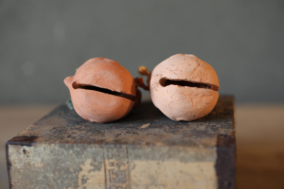 Two clay bells with a hole in the middle, sitting on a metal surface.