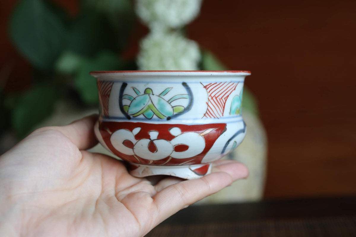 A hand holding a colorful ceramic bowl with intricate designs.