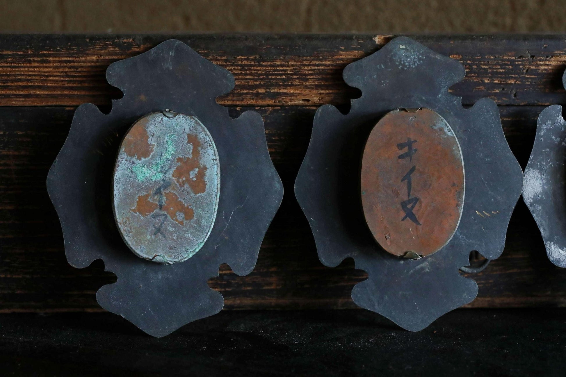 two oval-shaped metal objects with numbers and symbols on them, mounted on a wooden surface.