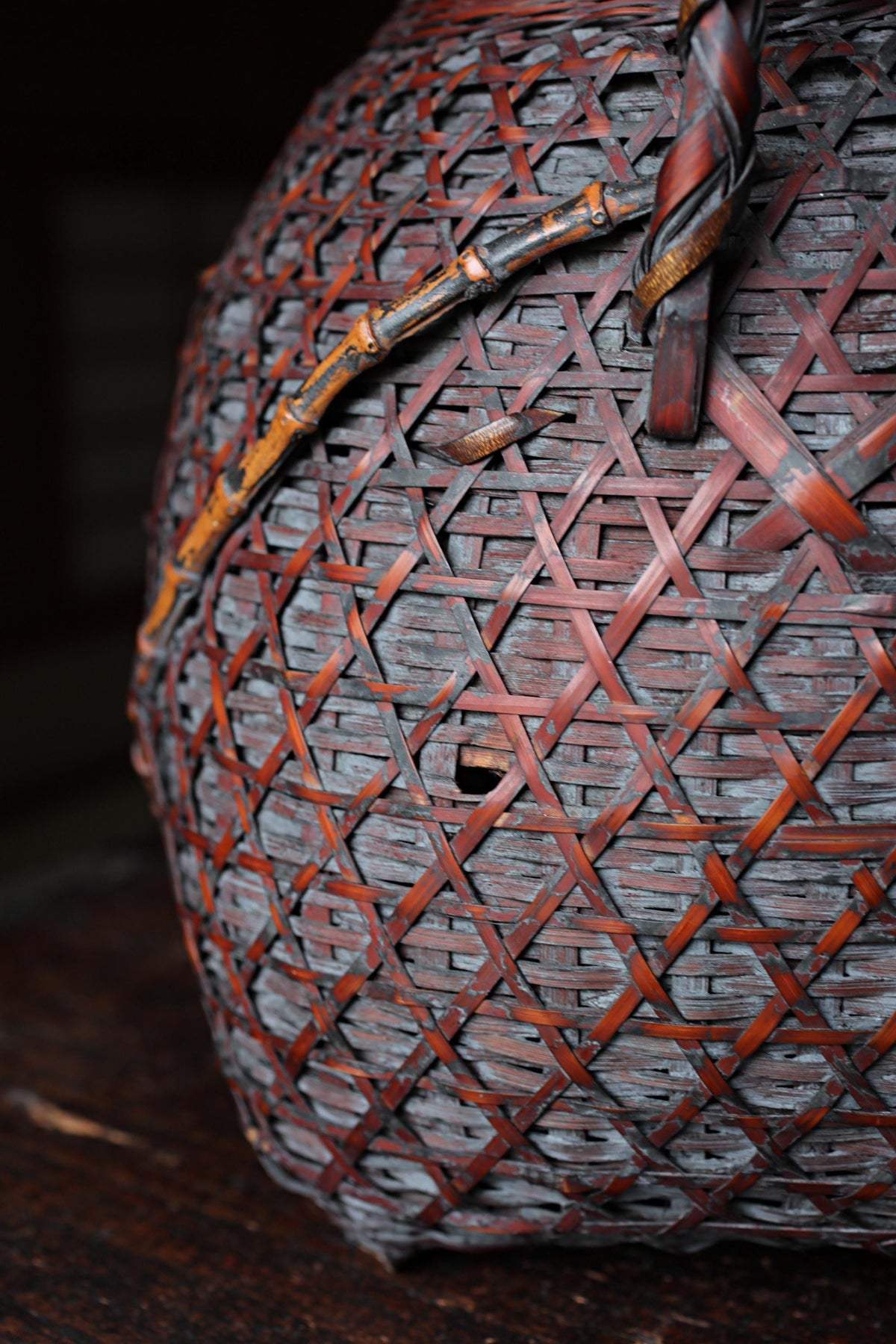 A close-up view of a woven basket with a distinctive pattern of red and brown interwoven threads.