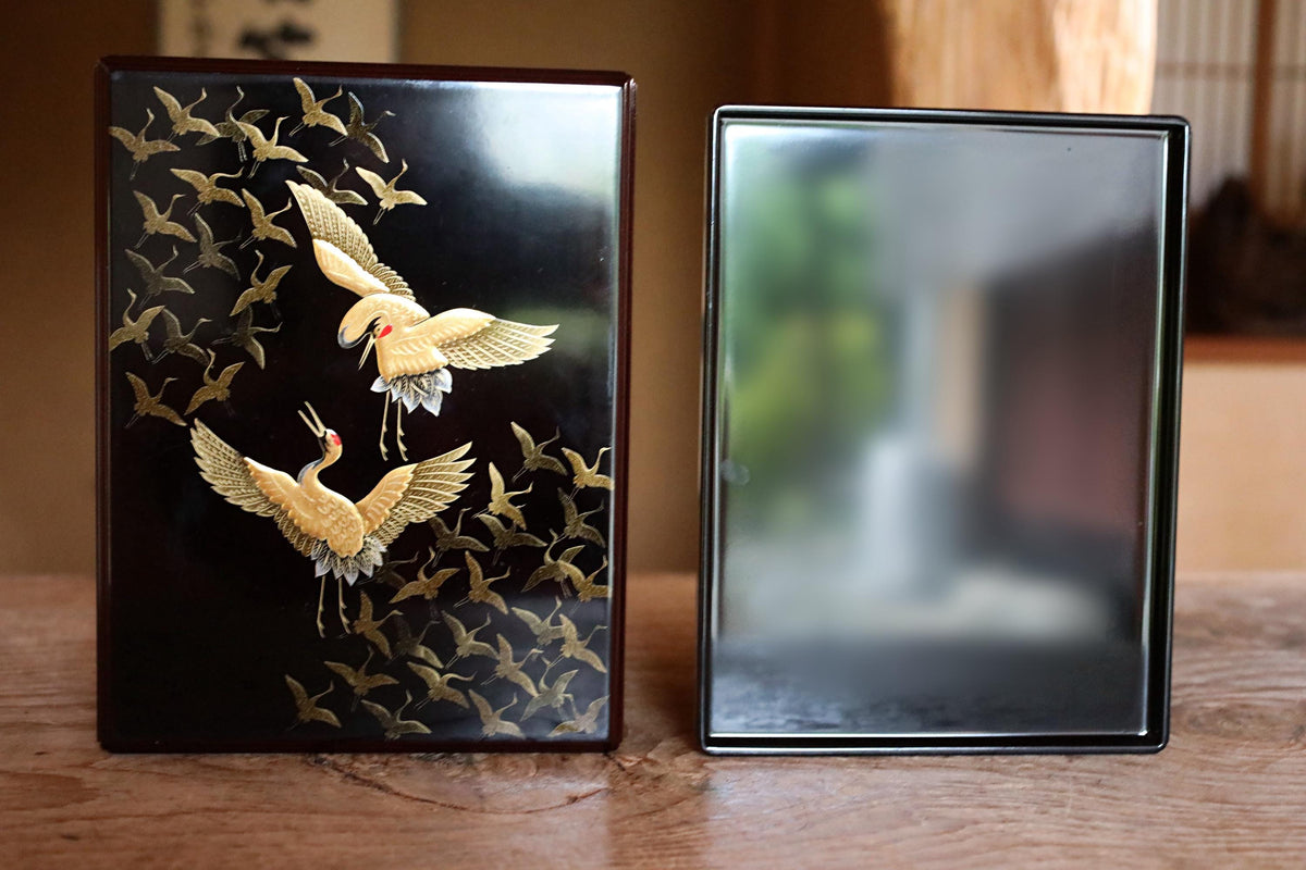two objects with gold designs on them, placed on a wooden surface.