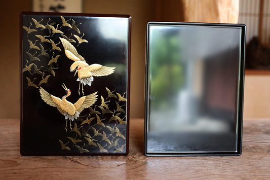 two objects with gold designs on them, placed on a wooden surface.