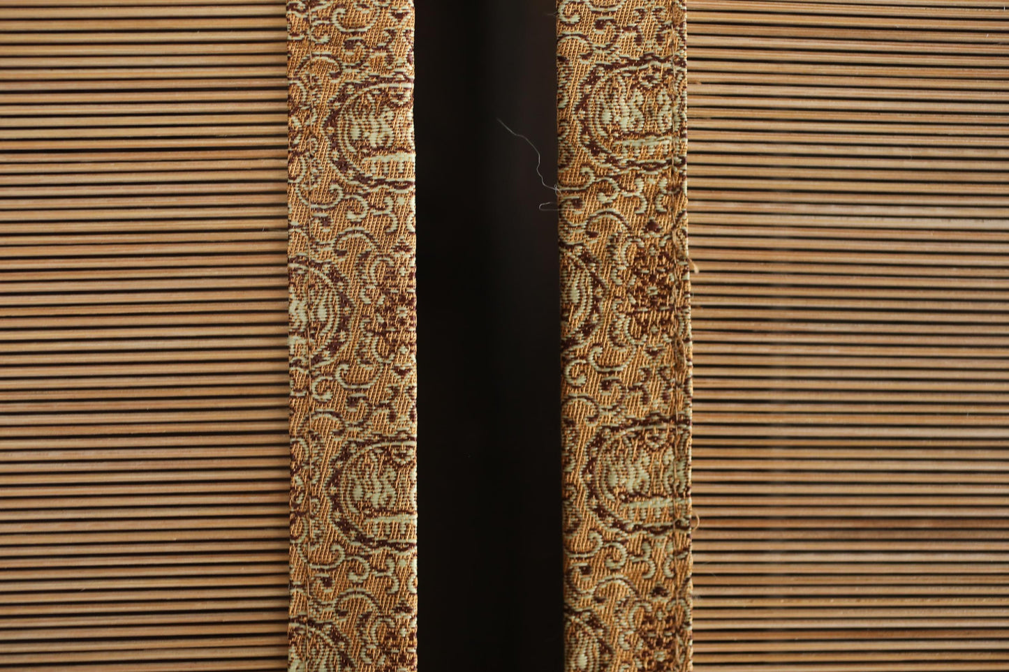 a close-up view of a patterned fabric, possibly a curtain or textile, with a dark background.