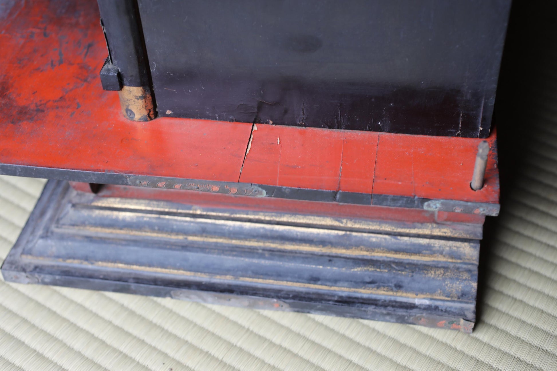 a close-up view of a wooden structure with a red and black color scheme. The structure appears to be made of wood and has a black metal frame. The image is taken from a low angle, emphasizing the height and structure of the wooden frame.