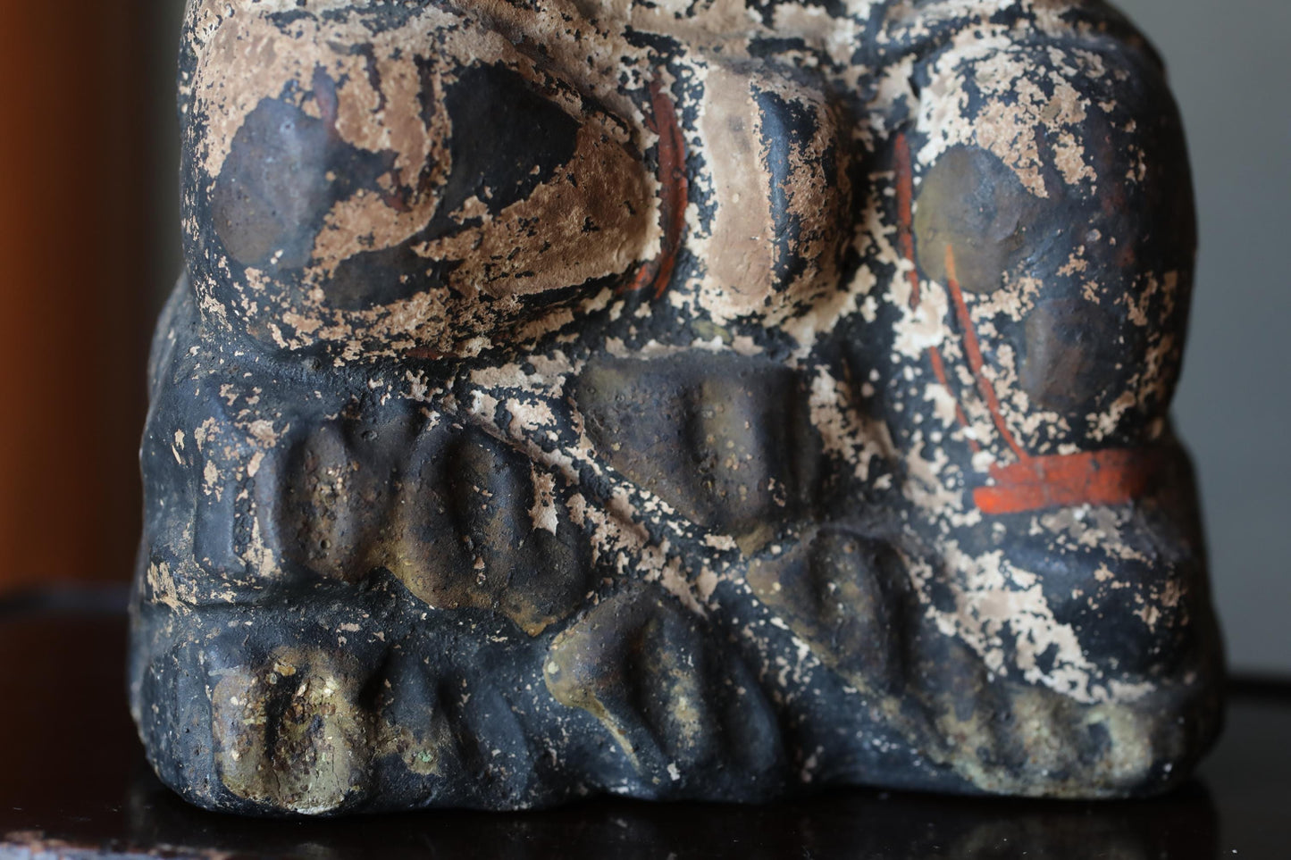 a close-up view of a weathered, black and brown statue or sculpture with a textured surface.