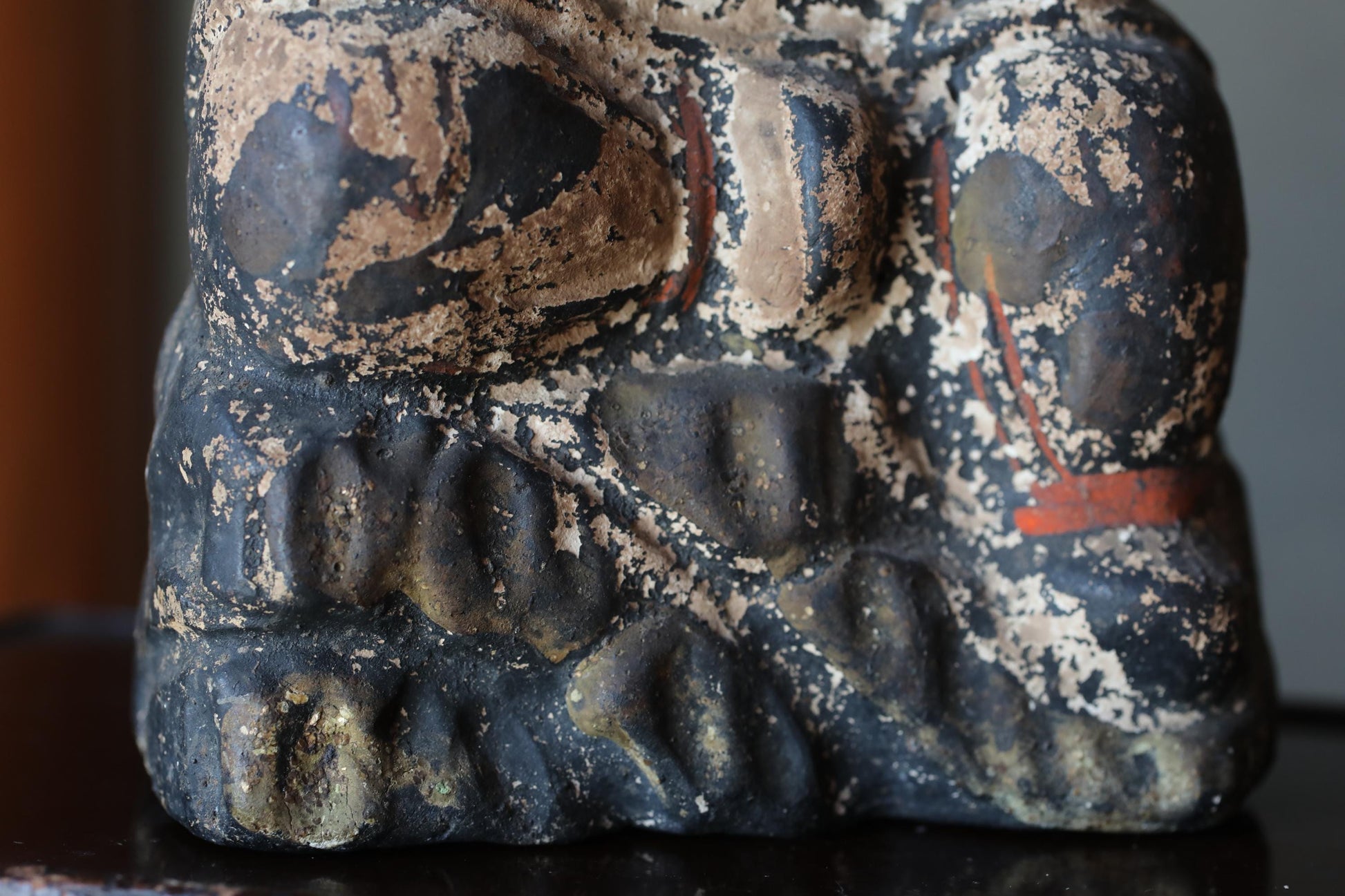 a close-up view of a weathered, black and brown statue or sculpture with a textured surface.