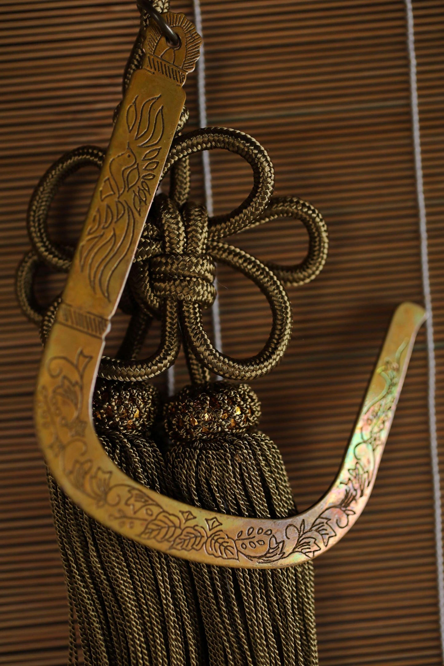 a decorative tassel with a floral design, hanging on a wooden surface.