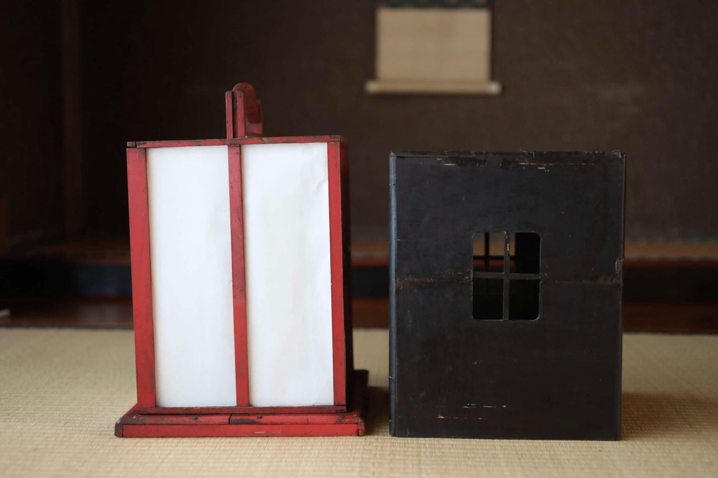 a red lantern and a black box, both sitting on a beige surface.