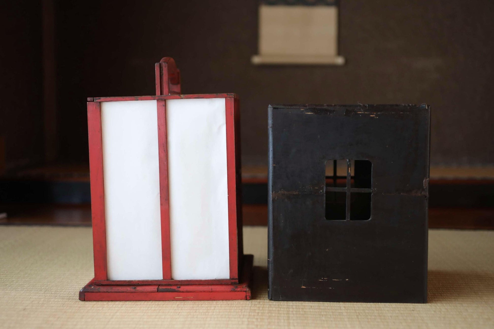 a red lantern and a black box, both sitting on a beige surface.