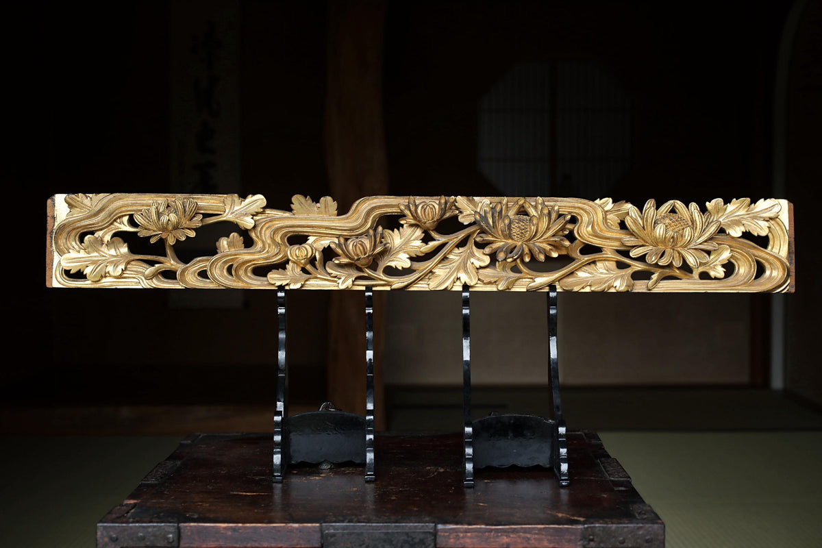 a decorative wooden panel with intricate floral designs, displayed on a wooden stand.
